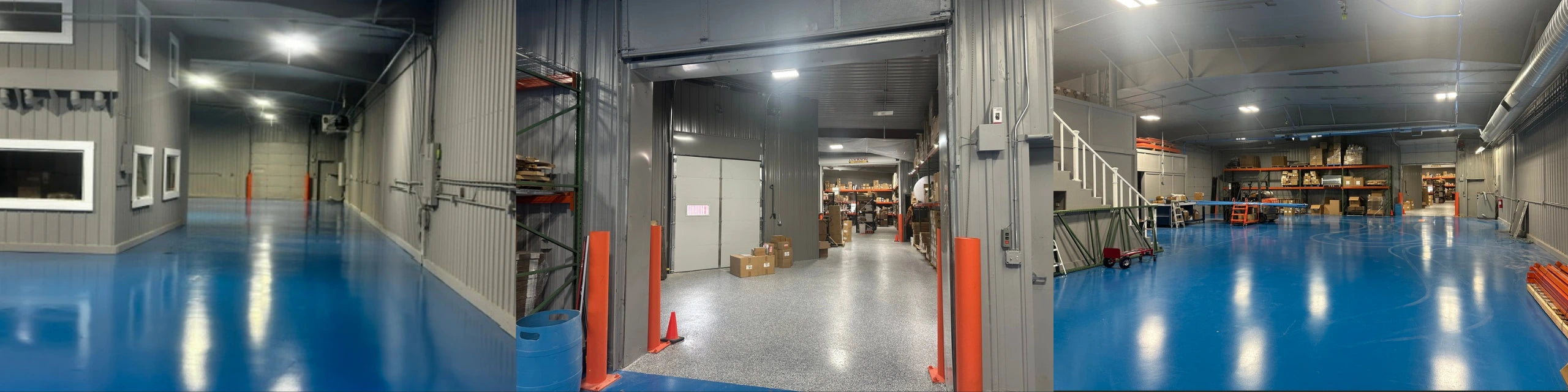 A panoramic view of a large indoor warehouse or industrial storage facility with a bright blue floor, gray metal walls, overhead lighting, shelving, and a partially open overhead door.